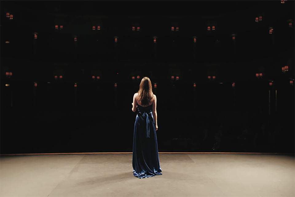 A student standing on stage in the RCM Britten Theatre